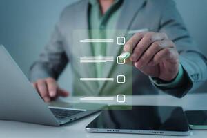 Businessman working on laptop and tablet productivity checklist and filling survey form online. Document management system DMS. Assessment form, questionnaire, Checklist and clipboard task management. photo