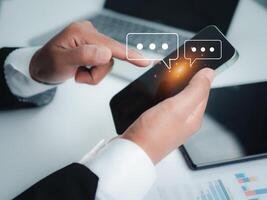 Human hand using smartphone typing, Chatting conversation in chat box icons pop up, Social media marketing concept, Chatting on application communication digital web and social network concept. photo