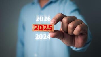 Businessman hand holding 2025 wooden block, Risk business and New Year New start concepts, 2025 goal planning, Countdown, business planning to 2025, Resolution, Strategy, Solution, Goal. photo