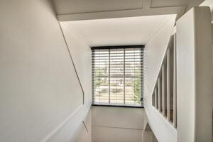 A narrow stairway with a window and a railing photo