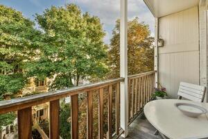 A balcony with a table and chairs overlooking a tree photo