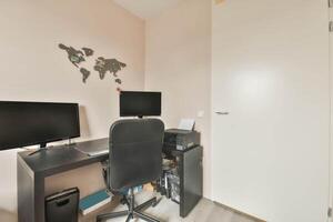 A home office with a desk, computer and a world map photo