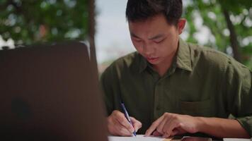 A man is writing on a piece of paper while sitting at a table video
