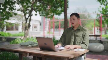 A man sitting at a table with a laptop video