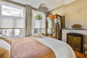 A bedroom with a bed, a fireplace and a window photo