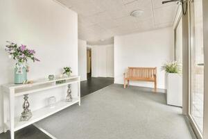 A hallway with a bench and a vase on the floor photo