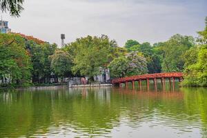 Hanoi, Vietnam - 26 June 2024 Red The Huc Bridge and Ngoc Son Temple in the center of Hoan Kiem Lake, Hanoi, Vietnam. Famous destination of Vietnam photo