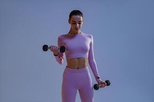Fitness woman doing exercises with dumbbells on studio background. Strength and motivation photo