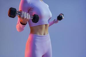 Close up of woman doing exercises with dumbbells on studio background. Strength and motivation photo