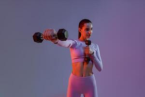 Fitness woman doing exercises with dumbbells on studio background. Strength and motivation photo