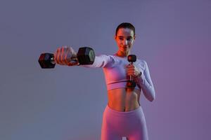 Pretty fitness woman doing exercises with dumbbells on studio background. Strength and motivation photo