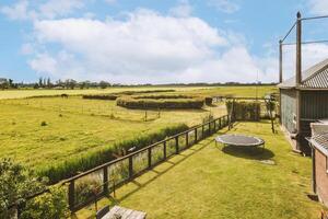 A view of a green field with a barn and a trampoline photo