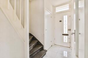 A hallway with a white door and stairs photo