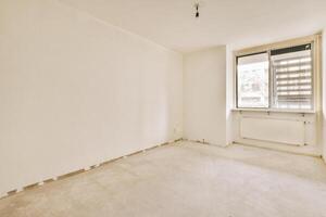An empty room with a window and a radiator photo