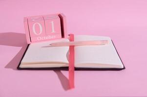Pink October calendar and notebook with pen on pink background emphasizing planning and organization photo
