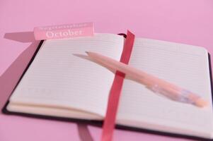 Open planner on pink background with September and October blocks with a pencil, ideal for scheduling and productivity themes photo