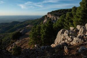 Scenic view of a rugged mountain landscape with lush green forests under a clear blue sky photo