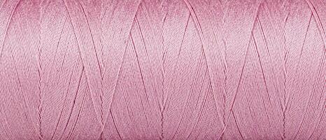 Texture of threads in a spool of pink color on a white background photo