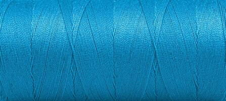 Texture of threads in a spool of blue color on a white background photo