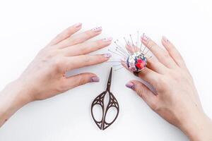 a ring with a small pillow for needles on a hand and scissors on a white background photo