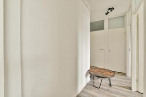 A white hallway with a wooden table and a chair photo