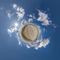 simple little tiny planet without buildings in blue sky with beautiful clouds. Transformation of spherical panorama 360 degrees. Spherical abstract aerial view. Curvature of space. photo