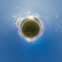 simple little tiny planet without buildings in blue sky with beautiful clouds. Transformation of spherical panorama 360 degrees. Spherical abstract aerial view. Curvature of space. photo
