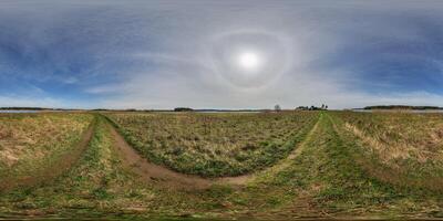 full seamless spherical hdri panorama 360 degrees angle view among fields in early spring day with sun on clear sky with halo in equirectangular projection, ready for VR AR content photo