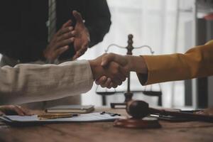 Lawyer shaking hands with a client making about documents, contracts, agreements, cooperation agreements with a female client at the lawyer's desk and a hammer at the table. photo