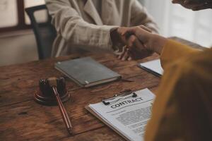 Lawyer shaking hands with a client making about documents, contracts, agreements, cooperation agreements with a female client at the lawyer's desk and a hammer at the table. photo