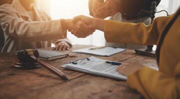 Lawyer shaking hands with a client making about documents, contracts, agreements, cooperation agreements with a female client at the lawyer's desk and a hammer at the table. photo