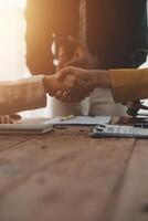 Lawyer shaking hands with a client making about documents, contracts, agreements, cooperation agreements with a female client at the lawyer's desk and a hammer at the table. photo
