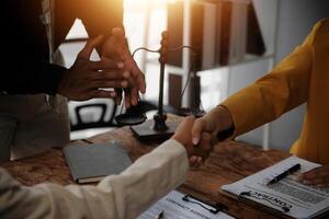 Lawyer shaking hands with a client making about documents, contracts, agreements, cooperation agreements with a female client at the lawyer's desk and a hammer at the table. photo