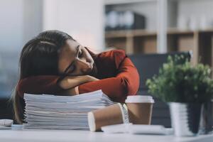 The business lady and the employee take a nap while working on the office desk. Working women are exhausted and sleeping on the table photo