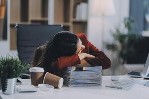 The business lady and the employee take a nap while working on the office desk. Working women are exhausted and sleeping on the table photo