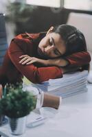 The business lady and the employee take a nap while working on the office desk. Working women are exhausted and sleeping on the table photo
