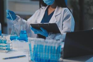 Group of dedicated scientist conduct chemical experiment in medical laboratory, carefully drop precise amount of liquid from pipette into test tube for vaccine drug or antibiotic development. Neoteric photo