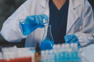 Group of dedicated scientist conduct chemical experiment in medical laboratory, carefully drop precise amount of liquid from pipette into test tube for vaccine drug or antibiotic development. Neoteric photo
