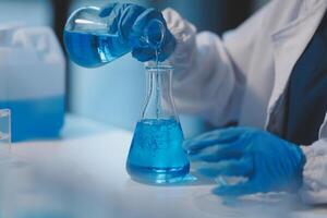 Group of dedicated scientist conduct chemical experiment in medical laboratory, carefully drop precise amount of liquid from pipette into test tube for vaccine drug or antibiotic development. Neoteric photo