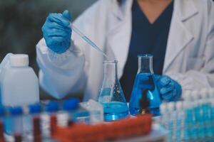 Group of dedicated scientist conduct chemical experiment in medical laboratory, carefully drop precise amount of liquid from pipette into test tube for vaccine drug or antibiotic development. Neoteric photo