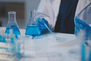 Group of dedicated scientist conduct chemical experiment in medical laboratory, carefully drop precise amount of liquid from pipette into test tube for vaccine drug or antibiotic development. Neoteric photo