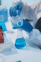 Group of dedicated scientist conduct chemical experiment in medical laboratory, carefully drop precise amount of liquid from pipette into test tube for vaccine drug or antibiotic development. Neoteric photo