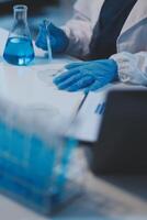Group of dedicated scientist conduct chemical experiment in medical laboratory, carefully drop precise amount of liquid from pipette into test tube for vaccine drug or antibiotic development. Neoteric photo