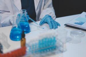Group of dedicated scientist conduct chemical experiment in medical laboratory, carefully drop precise amount of liquid from pipette into test tube for vaccine drug or antibiotic development. Neoteric photo