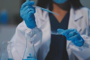 Group of dedicated scientist conduct chemical experiment in medical laboratory, carefully drop precise amount of liquid from pipette into test tube for vaccine drug or antibiotic development. Neoteric photo