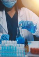 Group of dedicated scientist conduct chemical experiment in medical laboratory, carefully drop precise amount of liquid from pipette into test tube for vaccine drug or antibiotic development. Neoteric photo