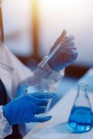 Group of dedicated scientist conduct chemical experiment in medical laboratory, carefully drop precise amount of liquid from pipette into test tube for vaccine drug or antibiotic development. Neoteric photo