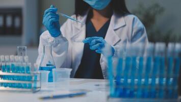 Group of dedicated scientist conduct chemical experiment in medical laboratory, carefully drop precise amount of liquid from pipette into test tube for vaccine drug or antibiotic development. Neoteric photo
