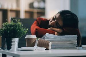 The business lady and the employee take a nap while working on the office desk. Working women are exhausted and sleeping on the table photo
