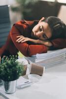 The business lady and the employee take a nap while working on the office desk. Working women are exhausted and sleeping on the table photo